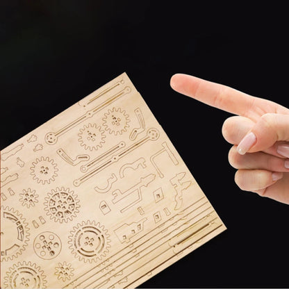 Laser-cut wooden parts sheet for a race car model, held by fingertips.