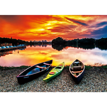 Three kayaks on a pebbled shore beside a lake at sunset, shown as the puzzle image