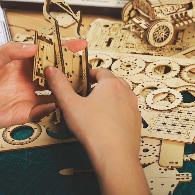 Wooden race car model parts being assembled by hands on a work surface.