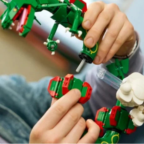 Hands adjusting red-and-green dragon segments near small white cloud elements