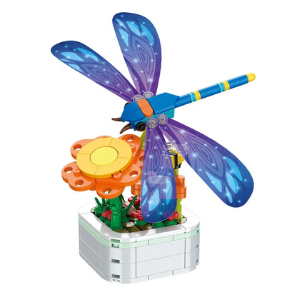 Blue dragonfly building set with green leaves on white block flower pot